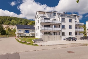 Ein mehrgeschossiges Wohngebäude mit Balkonen, einem Parkplatz und einem Schild, das eine familienfreundliche Umgebung kennzeichnet.