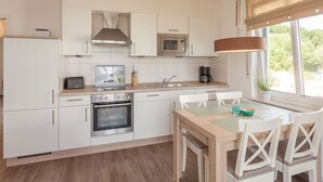 Eine moderne Küche mit weißen Schränken, einem eingebauten Backofen, einer Mikrowelle und einem Essbereich mit Tisch und Stühlen.