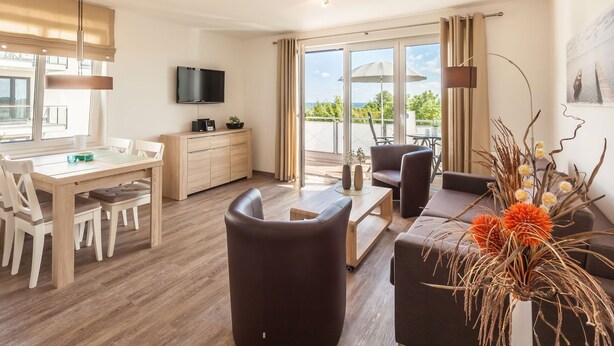 Ein modernes Wohnzimmer mit Essbereich, einem Flachbildfernseher und einem Balkon mit Blick.
