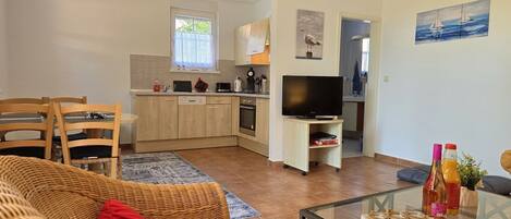 A compact living space with a dining area, kitchenette, and a television.
