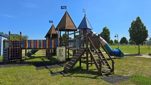 A playground with a slide, climbing structures, and a basketball hoop.