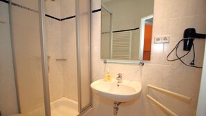 A bathroom with a glass-enclosed shower, a sink with a mirror, and a hairdryer on the wall. - Alter Reichshof, App. 305 with balcony and sea view - Alter Reichshof, App. 305 - (Sassnitz auf Rügen)