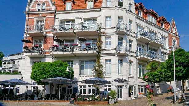 A multi-story hotel with balconies, outdoor seating, and a classic European architectural style. - Alter Reichshof, App. 305 with balcony and sea view - Alter Reichshof, App. 305 - (Sassnitz auf Rügen)