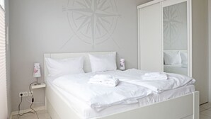 A white bed with pillows, a bedside lamp, and a wall-mounted compass design. - Alter Reichshof, App. 305 with balcony and sea view - Alter Reichshof, App. 305 - (Sassnitz auf Rügen)
