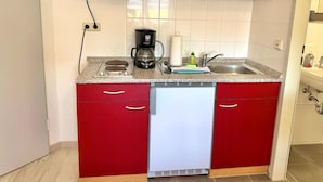 Eine kompakte Küche mit Geschirrspüler, Kaffeemaschine und Mikrowelle.