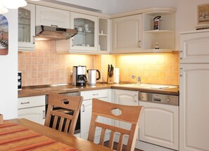 A kitchen with white cabinets, a coffee maker, a sink, and a dishwasher. - Villa Friede-Marie, App. Meeresidyll - with wonderful Baltic Sea view and balcony (Sassnitz auf Rügen)