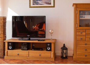 A television on a wooden stand with speakers, a remote control, and a wine glass beside it. - Villa Friede-Marie, App. Meeresidyll - with wonderful Baltic Sea view and balcony (Sassnitz auf Rügen)