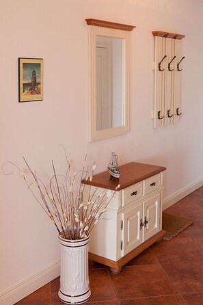 A hallway with a white cabinet, a mirror, and a coat rack. - Villa Friede-Marie, App. Meeresidyll - with wonderful Baltic Sea view and balcony (Sassnitz auf Rügen)