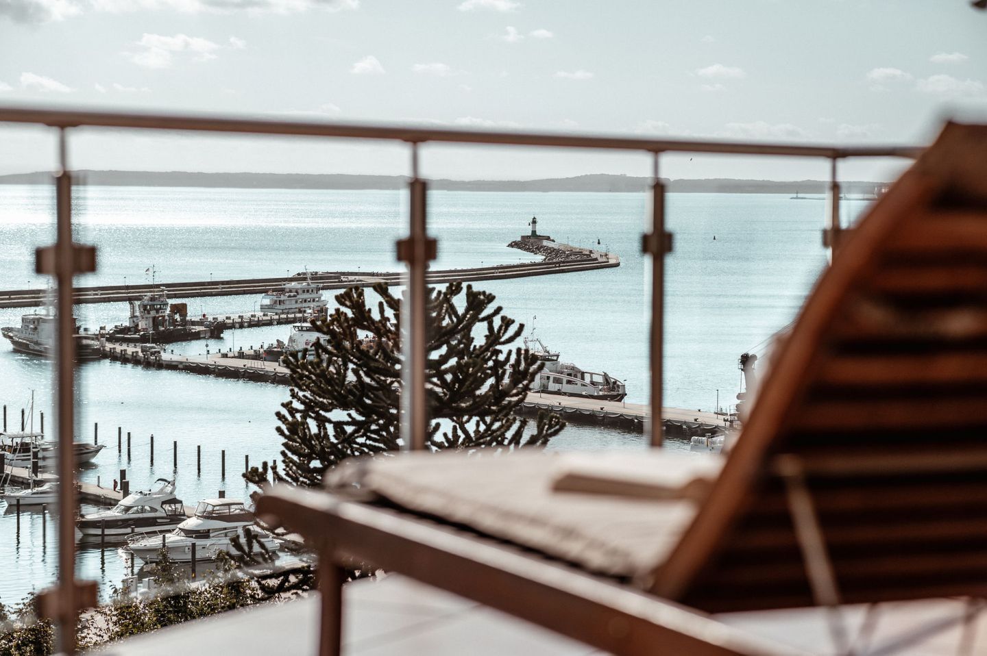 A balcony with a view of a harbor, including boats and a lighthouse.