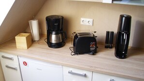 Eine Küchenzeile mit Kaffeemaschine, Toaster und einem kleinen Schrank.