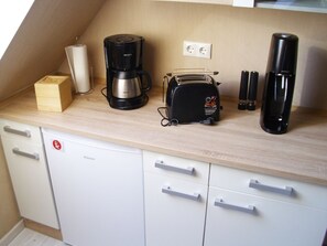 Eine Küchenzeile mit Kaffeemaschine, Toaster und einem kleinen Schrank.
