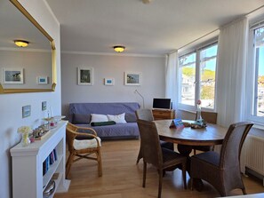 A room with a sofa, chairs, a dining table, a TV, and framed pictures on the wall. - Villa Seeblick App. 308 - with magnificent sea view - Villa Seeblick, App. 308 - (Sassnitz auf Rügen)