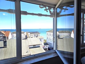 A view from a window overlooking a coastal town with buildings and the sea. - Villa Seeblick App. 308 - with magnificent sea view - Villa Seeblick, App. 308 - (Sassnitz auf Rügen)