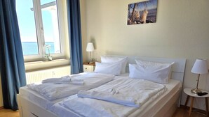 Una camera d'albergo con un letto, un comodino, una lampada, una finestra con tende e un quadro appeso al muro.