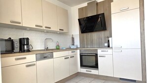 A modern kitchen with a microwave, coffee maker, sink, and oven. - Villa Johanna, App.2 - Bathing villa with magnificent sea view - Villa Johanna, App. (Sassnitz auf Rügen)