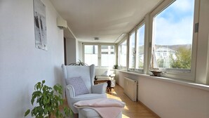 A bright room with a large window, a chair, a plant, and a radiator. - Villa Johanna, App.2 - Bathing villa with magnificent sea view - Villa Johanna, App. (Sassnitz auf Rügen)