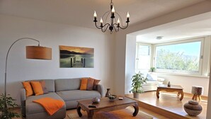 A modern living room with a sofa, coffee table, and a chandelier. - Villa Johanna, App.2 - Bathing villa with magnificent sea view - Villa Johanna, App. (Sassnitz auf Rügen)