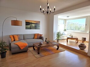 Ein modernes Wohnzimmer mit einer Couch, einem Couchtisch und einer Deckenleuchte.