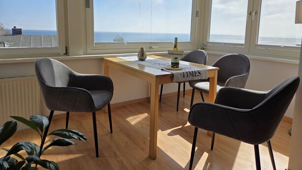 A room with a wooden table, four chairs, a bottle, and a welcome sign. - Villa Johanna, App.2 - Bathing villa with magnificent sea view - Villa Johanna, App. (Sassnitz auf Rügen)