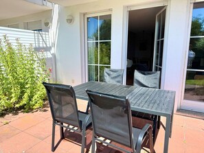 A patio with a table and chairs, a sliding glass door, and a small plant. - Vacation apartment Max - vacation in a quiet location with dog (Neddesitz auf Rügen)