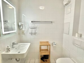 A bathroom with a white sink, mirror, towel rack, and a wooden shelf. - Vacation apartment Max - vacation in a quiet location with dog (Neddesitz auf Rügen)