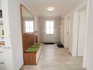 A hallway with a bench, a mirror, a door, and a window. - Reethaus Seeschwalbe - close to the beach - Reethaus Seeschwalbe close to the beach (Glowe auf Rügen)