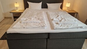 A double bed with two nightstands, each with a lamp, and a dark headboard. - Villa Monika, App. 5 Starboard - 2-room apartment with terrace and barbecue - (Sassnitz auf Rügen)