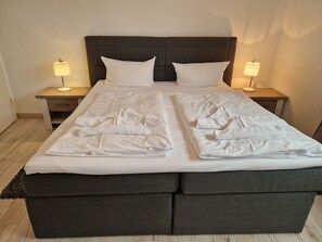 A double bed with two nightstands, each with a lamp, and a dark headboard. - Villa Monika, App. 5 Starboard - 2-room apartment with terrace and barbecue - (Sassnitz auf Rügen)