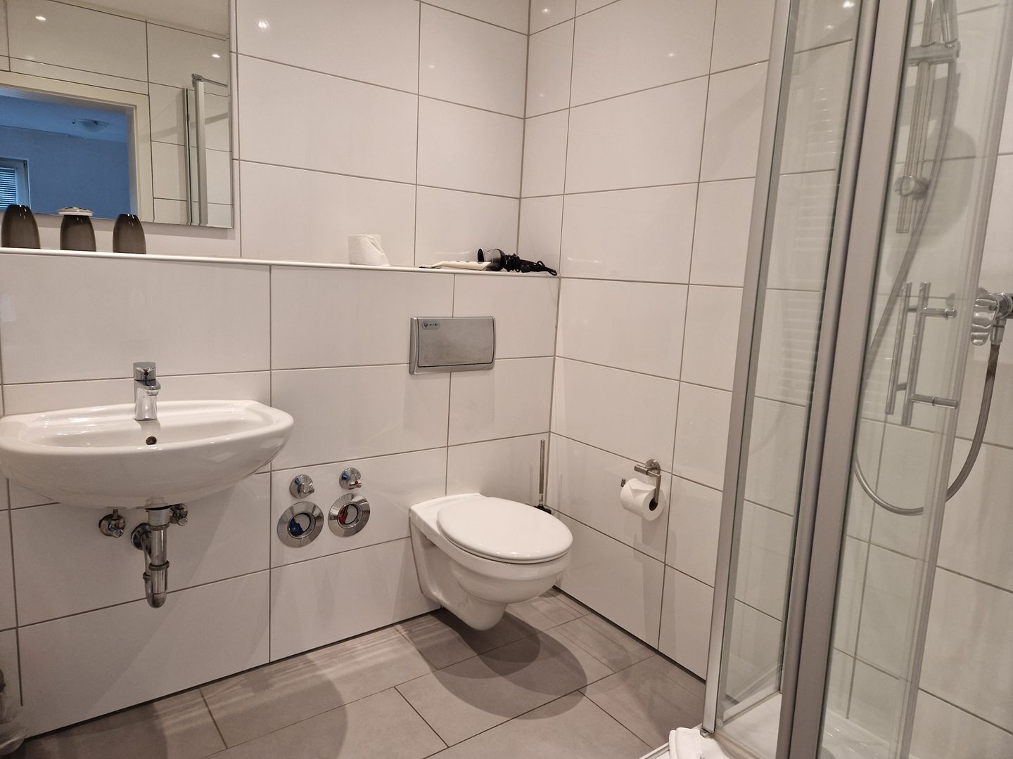 A modern bathroom with a sink, toilet, and glass shower enclosure.
