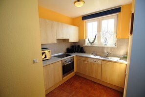 Eine kompakte Küche mit Holzausstattung, Backofen, Mikrowelle und einem Fenster mit Blick.