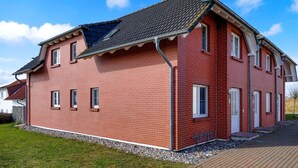 Ett hus byggt av rött tegel med ett sluttande tak, flera fönster och en synlig garageport.