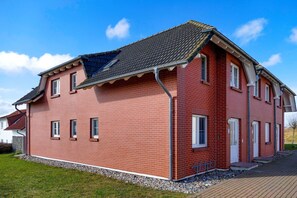 Ein rotes Backsteinhaus mit geneigtem Dach, mehreren Fenstern und einer sichtbaren Garagenöffnung.