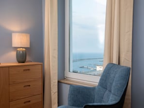 Ein Zimmer mit Blick auf einen Steg, ein Sessel, eine Lampe und eine Holzkommode.