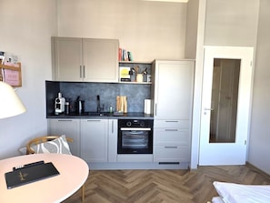 A compact kitchen with a built-in oven, a coffee machine, and a small countertop. - Alter Reichshof, Apartment 303 with Ocean View and Balcony - Ocean View & Balcony in Alt (Sassnitz auf Rügen)