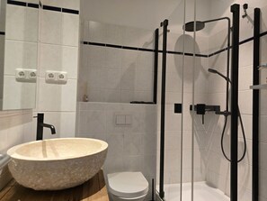 A modern bathroom with a large stone basin, a toilet, and a glass-enclosed shower area. - Alter Reichshof, Apartment 303 with Ocean View and Balcony - Ocean View & Balcony in Alt (Sassnitz auf Rügen)