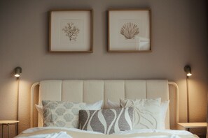 Ein Bett mit Kopfteil, zwei gerahmte Wandbilder und Nachttischlampen.