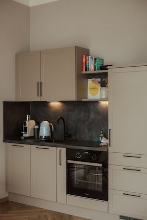 Eine kompakte Küche mit Einbauofen, Kaffeemaschine und Wasserkocher.