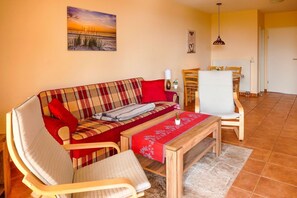 Ein Wohnzimmer mit einer Couch, Sesseln, einem kleinen Tisch und einem Gemälde an der Wand.