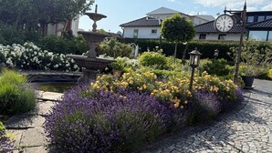 A garden with a fountain, flower beds, and a clock. - Villa Seestern, apartment 1 - pure sea view! - Villa Seestern, vacation apartment 1 - (Sassnitz)