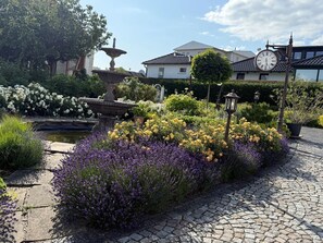 A garden with a fountain, flower beds, and a clock. - Villa Seestern, apartment 1 - pure sea view! - Villa Seestern, vacation apartment 1 - (Sassnitz)