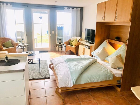 A bedroom with a bed, a TV, a desk, and a chair.