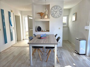 Ein stilvoller Essbereich mit Holztisch, Stühlen, einer Uhr und einer kleinen Küchenzeile mit Kühlschrank.