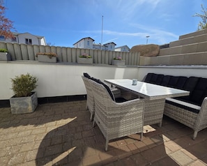 Eine Terrassengaststätte mit Korbmöbeln, einem Tisch und Topfpflanzen.