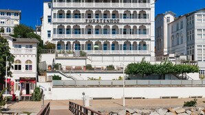 A multi-story building with balconies, a sign reading 'FURSTENHOFF,' and a wooden walkway leading to it. - Fürstenhof, App.104 - First row by the sea - Fürstenhof, App. 104 - First row (Sassnitz auf Rügen)