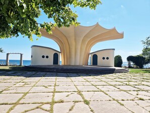 A symmetrical architectural structure with a central archway and two smaller arches on either side, set on a paved area with grass patches. - Fürstenhof, App.104 - First row by the sea - Fürstenhof, App. 104 - First row (Sassnitz auf Rügen)