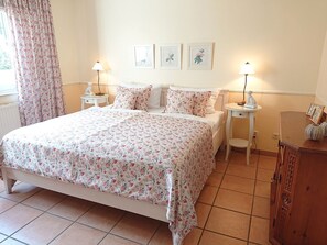 Ein Schlafzimmer mit einem Bett, zwei Nachttischen, einer Lampe, einem Wandbild und einem Schrank.