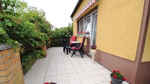 Un patio con tavolo e sedie, un muro in mattoni e piante in vaso.