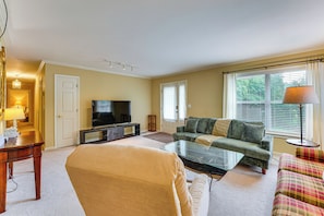 A living room with a sofa, a glass coffee table, a television, and a lamp. - 7 Mi to Lake Chatuge! Family Home w/ Office & Yard (Hayesville)