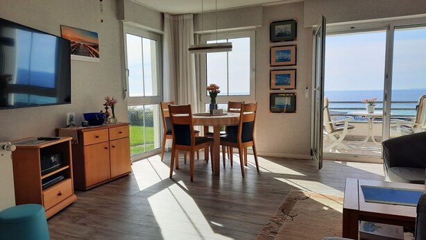 A modern living room with a dining area, a TV, and a view of the sea. - Apartment Kapitänsmesse - fantastic view over the harbor and the sea - (Sassnitz auf Rügen)