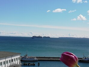 Ein großes Kreuzfahrtschiff in der Ferne, ein anlegender Bootsanleger und ein Gebäude mit Blick auf das Wasser.